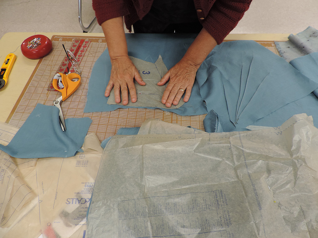 A womans hands smoothing a sewing pattern before pinning it to fabric